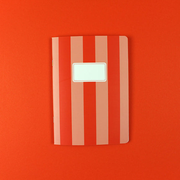 Ava & Yves Notizheft A5 mit rosa-rotem Streifendesign und Namensfeld auf dem Cover.