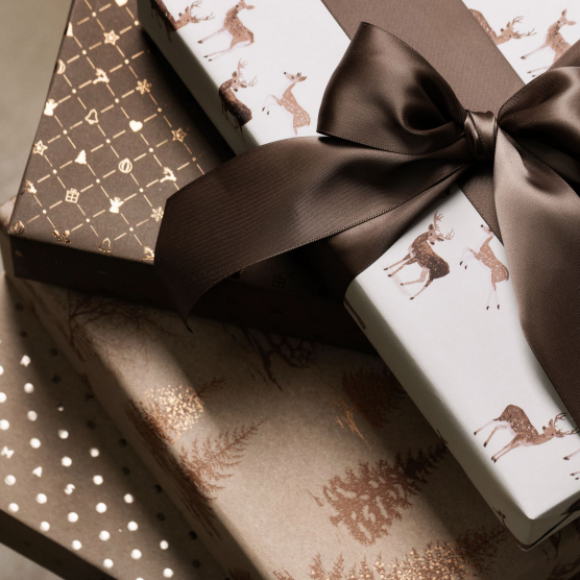 Geschenke in Naturtönen mit Rentiermuster und brauner Schleife.
