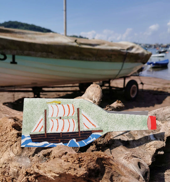 Karte in Flaschenform mit Segelschiff im Mid-Century-Stil; 23 × 7,5 cm, 300-g/m² Karton, elfenbeinfarbener Umschlag im Hintergrund.