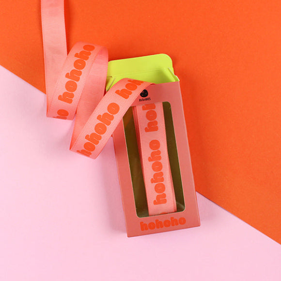 Ava & Yves Geschenkband Hohoho in Rosa mit rotem Schriftzug, 20 mm breit und 5 m lang, in dekorativer Verpackung.
