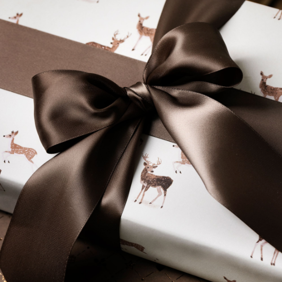 Geschenkpapier mit Rehen im Schnee und brauner Schleife