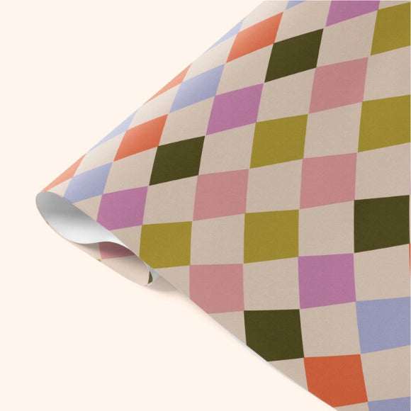 Buntes Geschenkpapier im modernen Harlekin-Rautenmuster, aufgerollt, mattes recyceltes Papier.